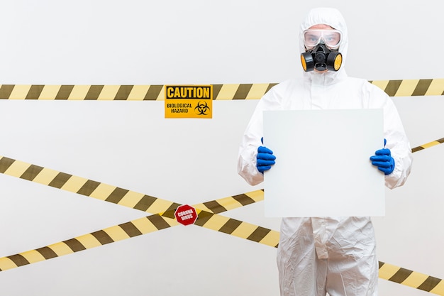 Homem em traje de proteção com um sinal em branco