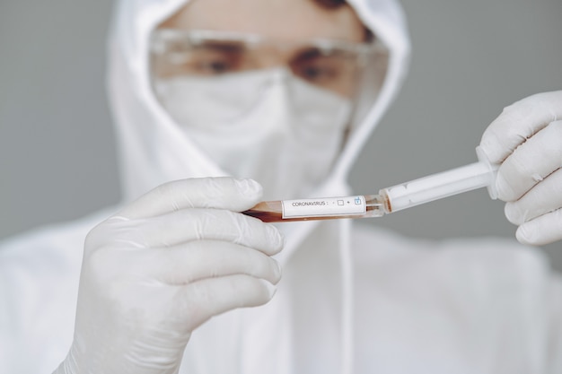 Homem em traje de proteção e óculos trabalhando no laboratório