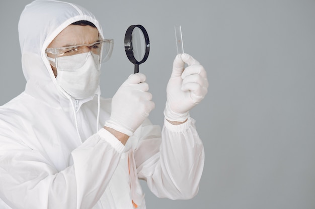 Homem em traje de proteção e óculos trabalhando no laboratório