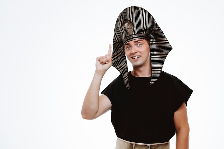 Foto grátis homem em traje egípcio antigo com um sorriso no rosto inteligente apontando com o dedo indicador para cima, tendo uma nova ideia em branco