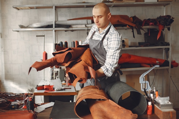 Foto grátis homem em um estúdio cria artigos de couro