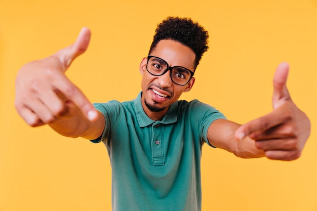 Homem emocional de olhos pretos posando. um cara africano inspirado com cabelo curto, fazendo caretas engraçadas.