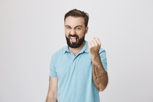 Homem engraçado brincalhão mostrando a língua e sacudindo o punho em um gesto que eu mostro