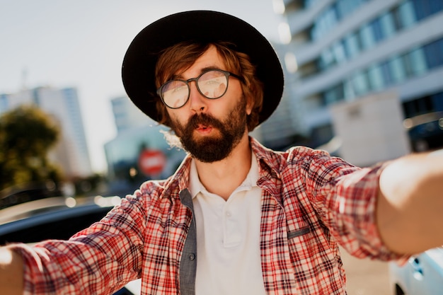 Foto grátis homem engraçado com barba fazendo auto-retrato pela câmera enquanto ele viaja na grande cidade moderna na ásia.