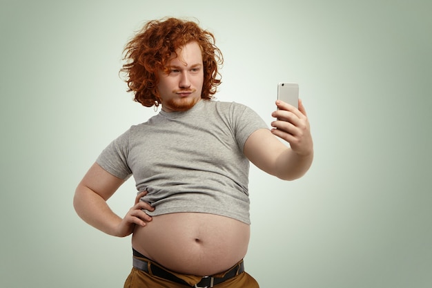 Foto grátis homem engraçado com sobrepeso e barriga gorda saindo de uma camiseta cinza