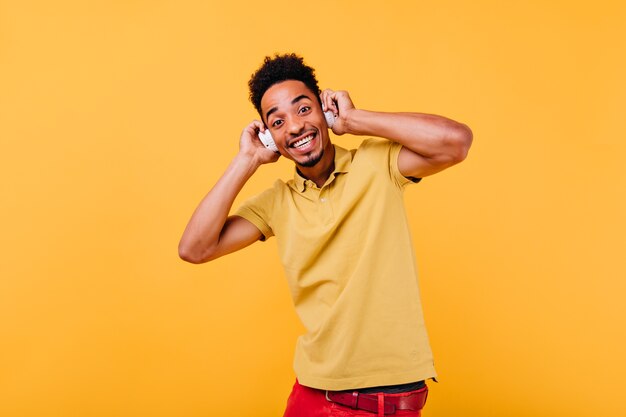 Homem engraçado de olhos pretos tocando seus fones de ouvido. incrível modelo africano ouvindo música.