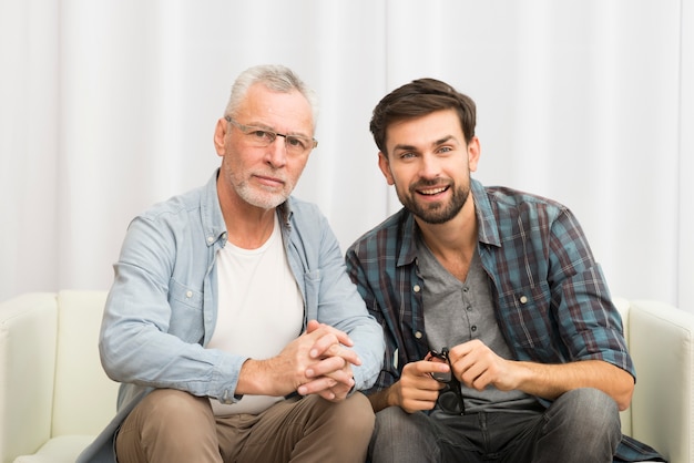 Homem envelhecido e jovem feliz, apertando as mãos no sofá