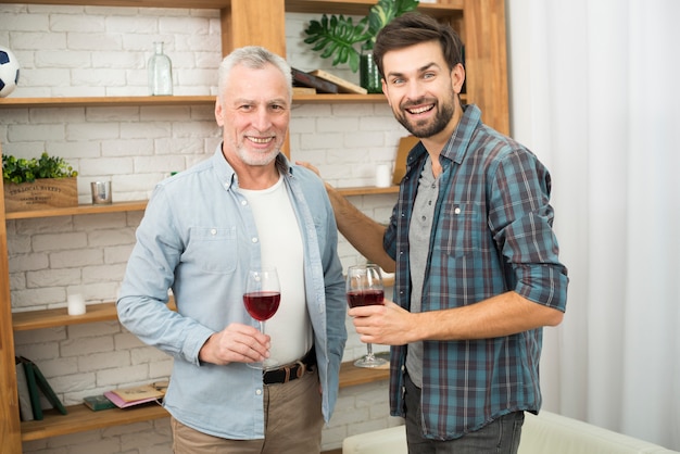 Homem envelhecido e jovem sorridente com copos de vinho