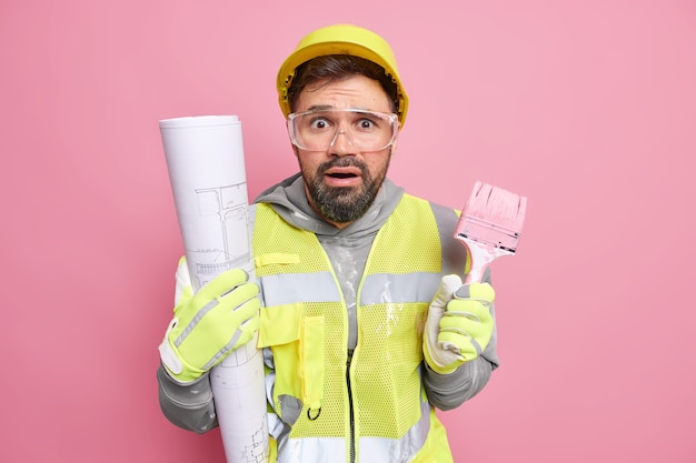 Foto grátis homem envolvido no trabalho de reforma de casa fornece serviço de reparo profissional segura pincel de pintura faz projeto arquitetônico usa roupas de proteção