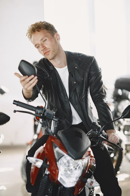 Homem escolheu motocicletas na loja de motos. Cara com uma jaqueta preta.