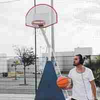 Foto grátis homem, escutar música, ligado, headphone, segurando, basquetebol, em, corte