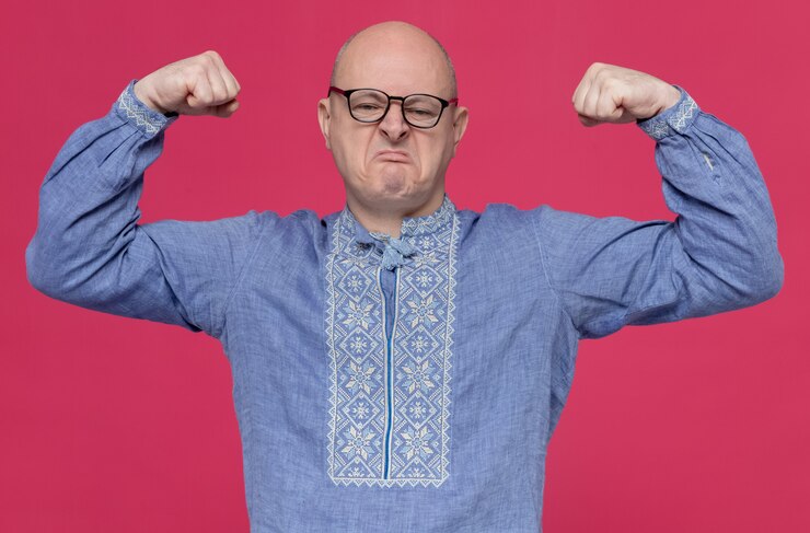 Foto grátis homem eslavo adulto confiante com camisa azul e óculos ópticos tensionando os bíceps