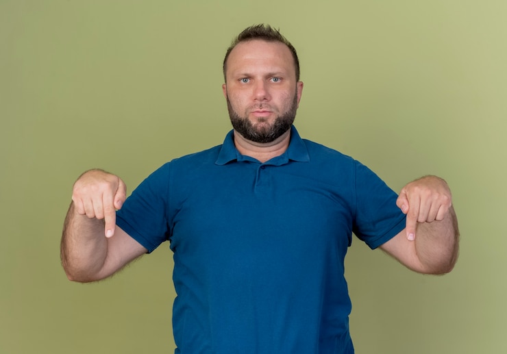 Foto grátis homem eslavo adulto estrito apontando para baixo