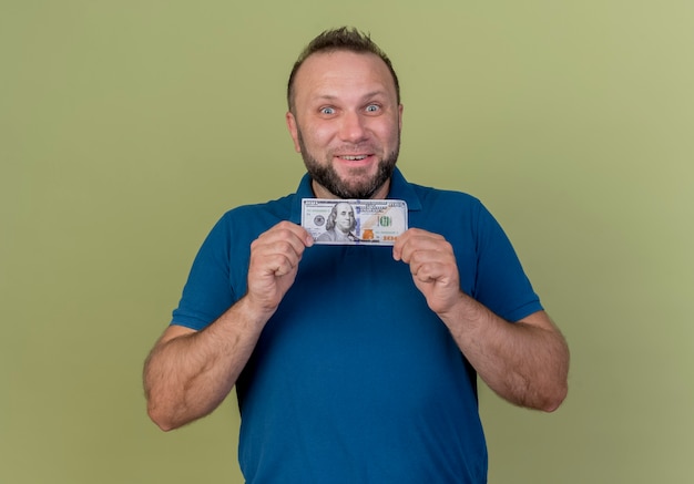 Foto grátis homem eslavo adulto sorridente segurando dinheiro olhando