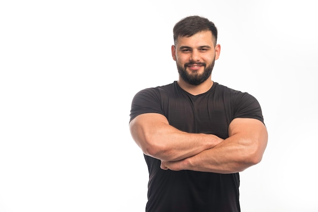 Foto grátis homem esportivo com camisa preta fechando os músculos do braço