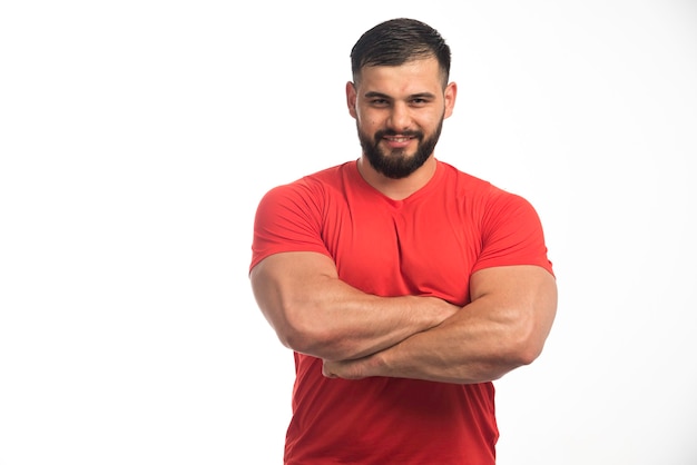 Foto grátis homem esportivo em vermelho, mostrando seus músculos.