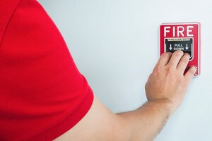 Foto grátis homem está chegando a mão para empurrar a estação de mão de alarme de incêndio