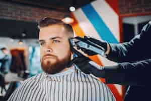 Foto grátis homem estiloso sentado em uma barbearia