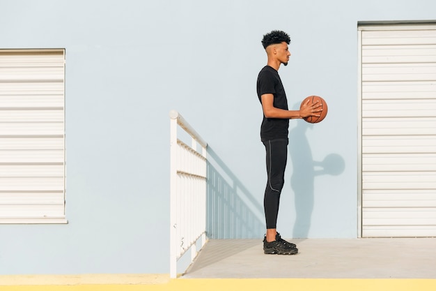 Homem étnico moderno com basquete na rua