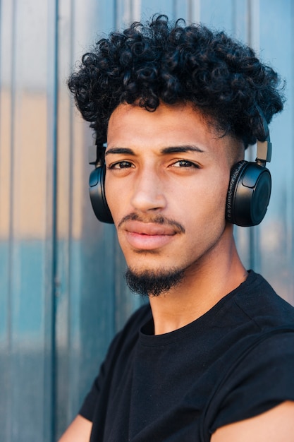 Homem étnico sério com cabelo encaracolado e fones de ouvido