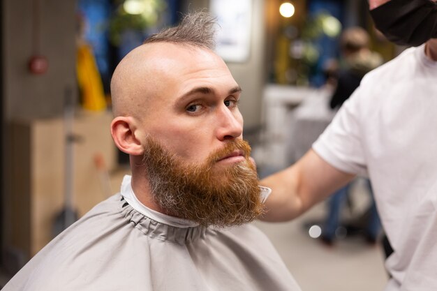 Homem europeu brutal com barba cortada em uma barbearia