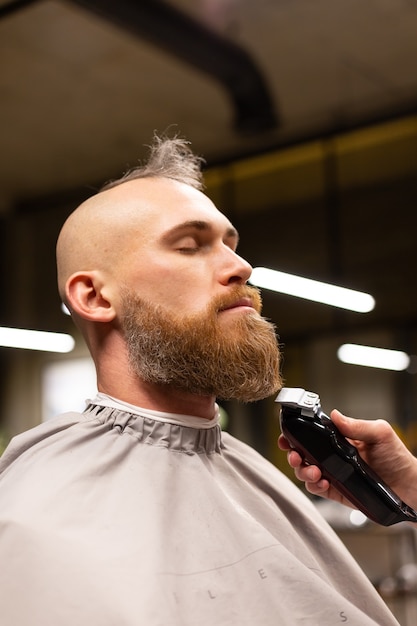 Homem europeu brutal com barba cortada em uma barbearia