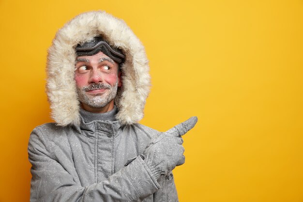 Homem europeu com a barba por fazer satisfeito sugere que participe de uma competição de corrida de esqui e use agasalhos cinza no espaço da cópia