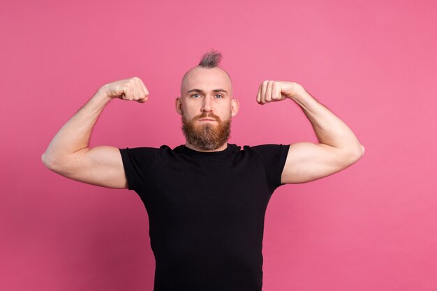 Homem europeu forte em fundo rosa mostrando músculos