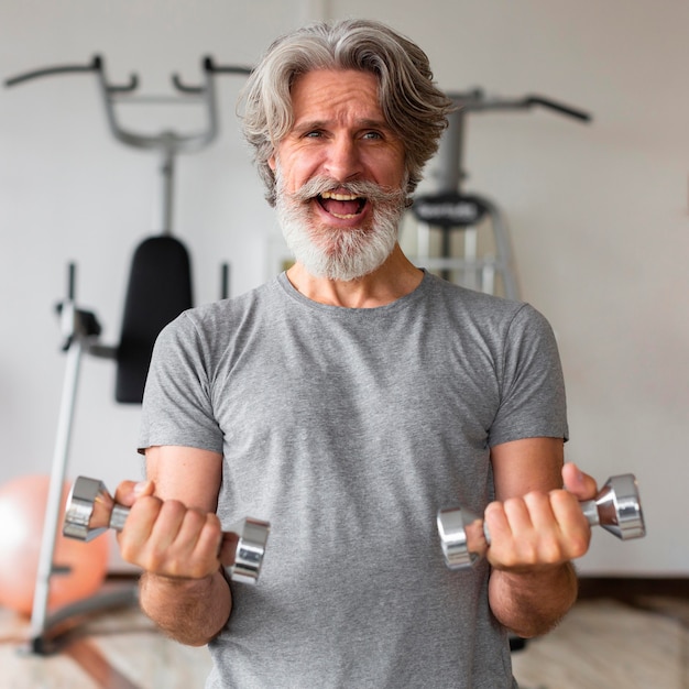 Foto grátis homem excitado segurando halteres