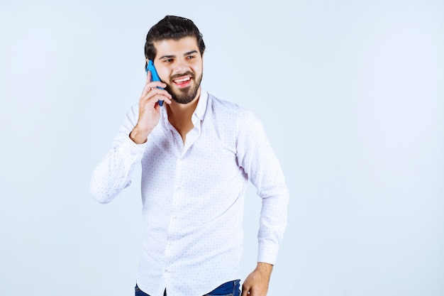 Homem falando com seu novo modelo de smartphone azul