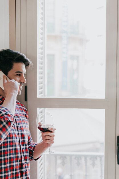 Homem falando no telefone e tendo vinho