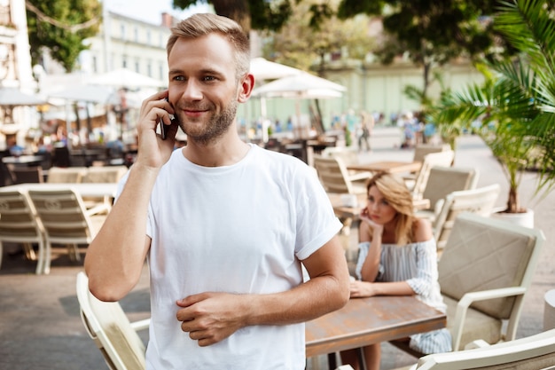 Homem falando no telefone enquanto sua namorada está entediada.