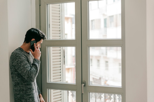 Homem falando no telefone perto da janela