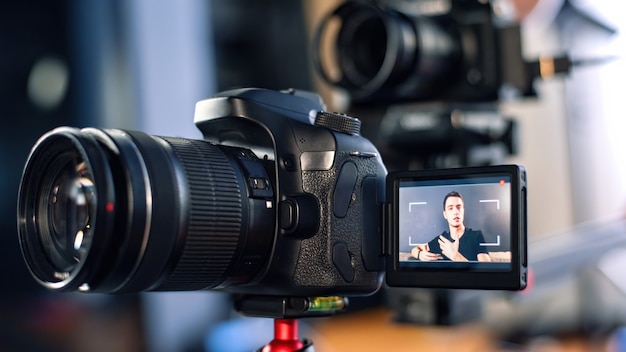 Homem falando para a câmera, gravando a si mesmo em um vlog. Trabalhando em casa. Jovem criador de conteúdo. Câmeras múltiplas