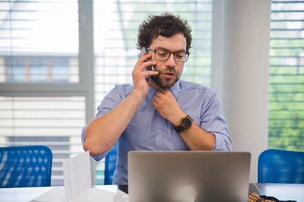 Foto grátis homem falando telefone enquanto trabalha com laptop