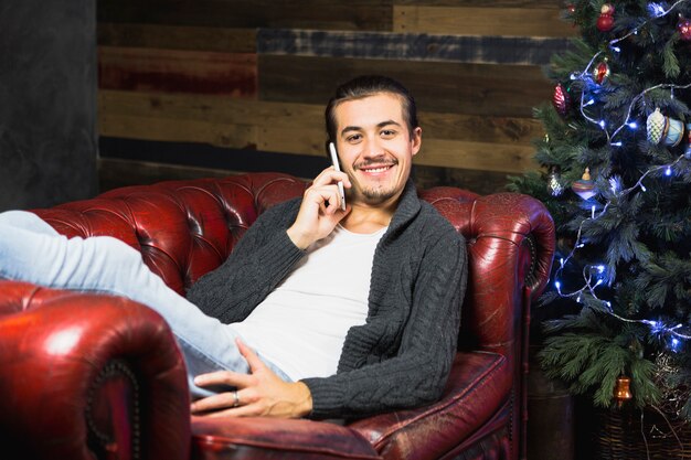Homem fazendo chamada de telefone no sofá no Natal
