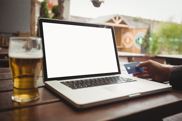 Homem fazendo compras on-line com cartão de crédito no laptop