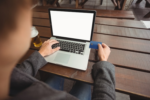 Homem fazendo compras on-line com cartão de crédito no laptop