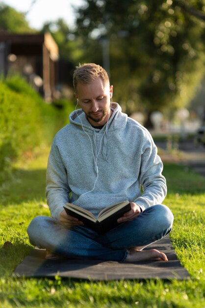 Homem fazendo posição de lótus enquanto lê um livro