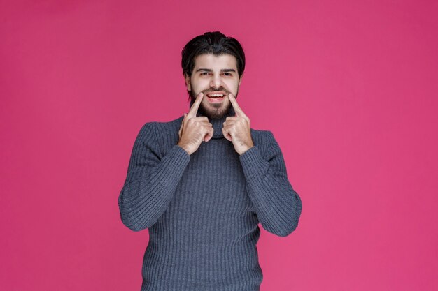 Homem fazendo sinal para um rosto sorridente e alegre.