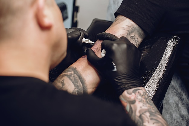 Homem fazendo uma tatuagem em um salão de tatuagem