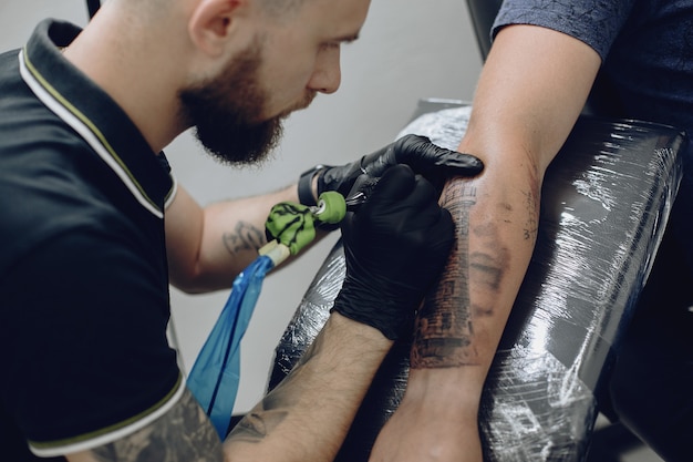 Foto grátis homem fazendo uma tatuagem em um salão de tatuagem