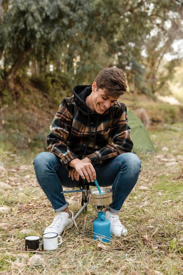 Foto grátis homem feliz acampando na floresta fazendo comida vista frontal