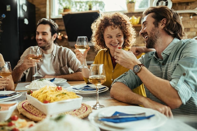 Homem feliz alimentando sua namorada enquanto almoçava com amigos em casa