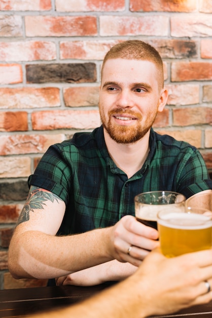 Homem feliz brindando copos alcoólicos em bar