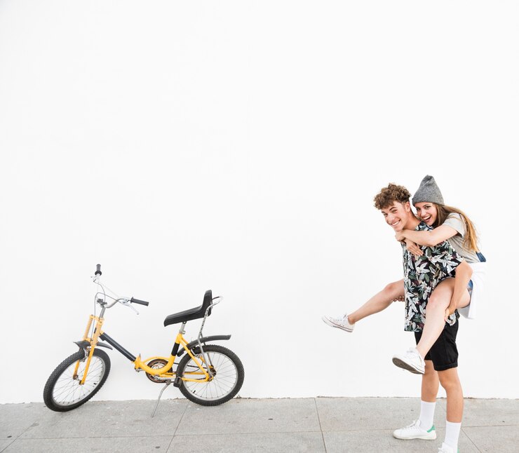 Foto grátis homem feliz, dar, carona piggyback, para, seu, namorada, perto, bicicleta amarela