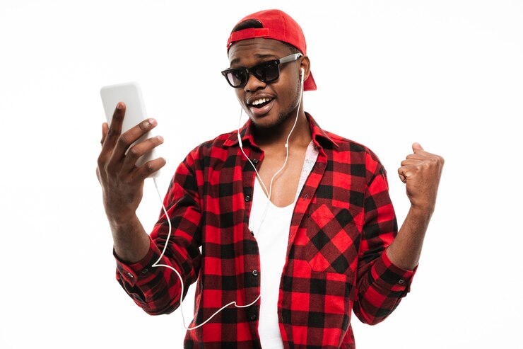 Foto grátis homem feliz, de pé e ouvindo música do telefone celular