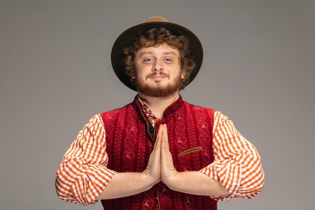 Foto grátis homem feliz e sorridente, vestido com o traje tradicional austríaco ou bávaro, gesticulando isolado em cinza