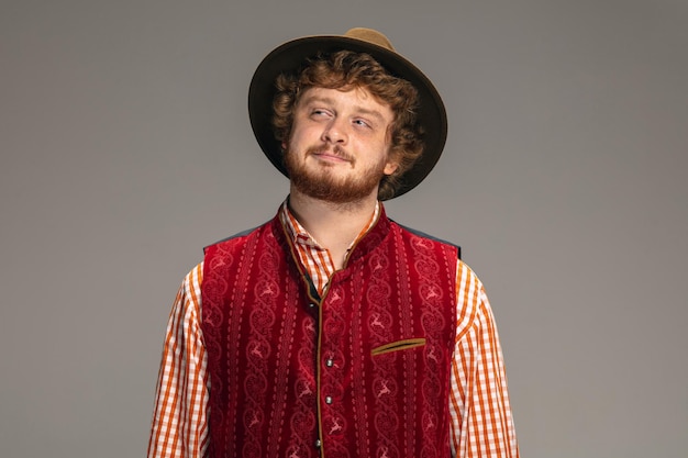 Homem feliz e sorridente, vestido com um traje tradicional austríaco ou bávaro, gesticulando isolado em cinza