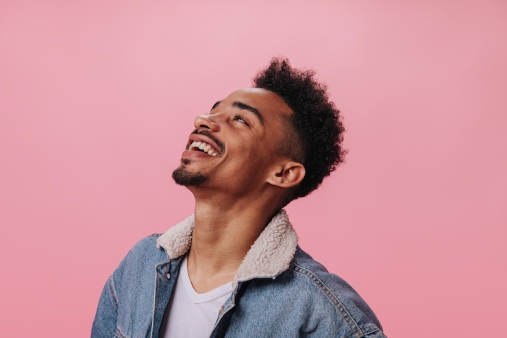 Foto grátis homem feliz em roupa jeans sorrindo em fundo rosa cara morena alegre em camiseta branca rindo em pano de fundo isolado